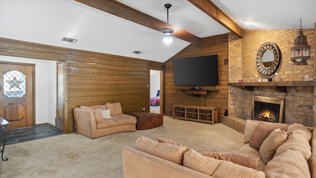 carpeted living room featuring ceiling fan, lofted ceiling with beams, a fireplace, and wooden walls