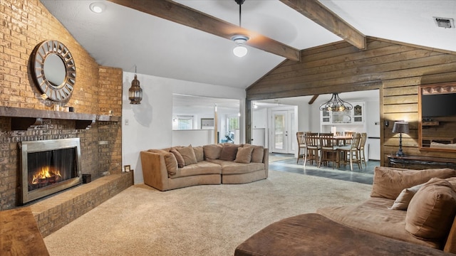 carpeted living room featuring a fireplace and vaulted ceiling with beams