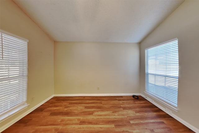 spare room with vaulted ceiling and hardwood / wood-style flooring