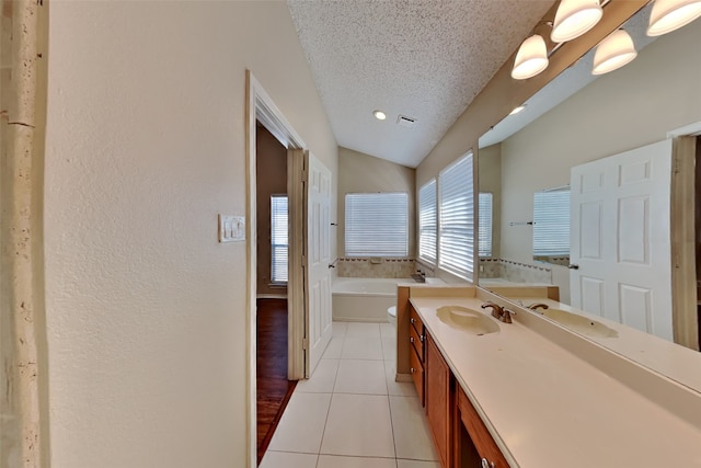 bathroom with a textured ceiling, vanity, a bath, tile patterned floors, and lofted ceiling