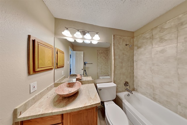 full bathroom with tiled shower / bath combo, vanity, toilet, and a textured ceiling