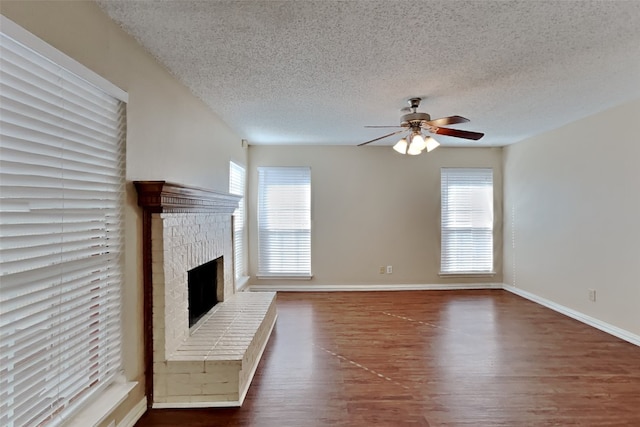 unfurnished living room featuring a textured ceiling, ceiling fan, hardwood / wood-style floors, and a fireplace