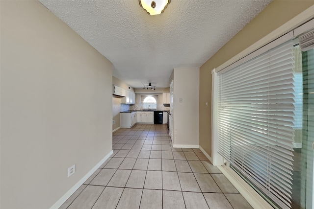 hall with light tile patterned flooring and a textured ceiling