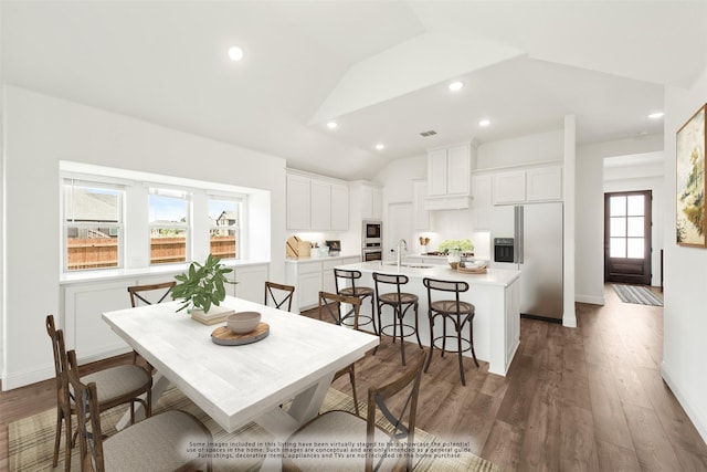 dining area featuring lofted ceiling, sink, and dark wood-type flooring