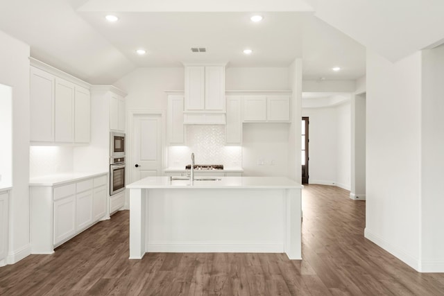 kitchen featuring a kitchen island with sink, oven, and white cabinets