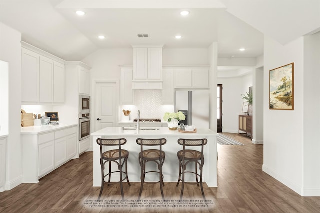 kitchen with white cabinetry, appliances with stainless steel finishes, a kitchen island with sink, and a kitchen bar