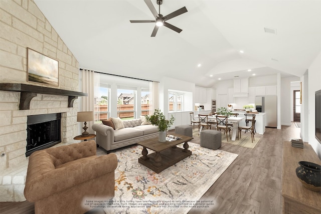 living room featuring hardwood / wood-style floors, a stone fireplace, high vaulted ceiling, and ceiling fan