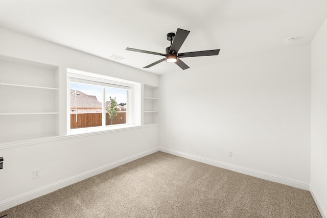 carpeted spare room with built in features and ceiling fan