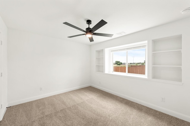 carpeted spare room with ceiling fan and built in features