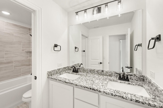 full bathroom featuring vanity, tiled shower / bath, and toilet