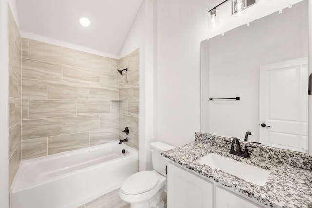 full bathroom featuring tiled shower / bath, vanity, toilet, and vaulted ceiling