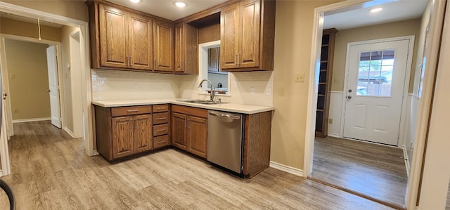 kitchen with tasteful backsplash, light hardwood / wood-style floors, sink, and stainless steel dishwasher