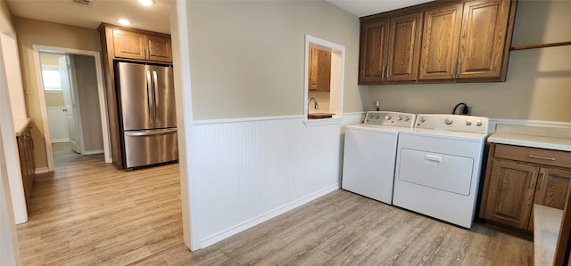 washroom featuring cabinets, light hardwood / wood-style floors, and washer and dryer