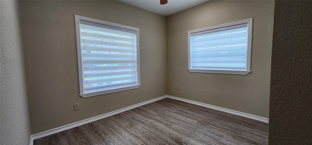 spare room featuring ceiling fan, dark hardwood / wood-style floors, and a healthy amount of sunlight