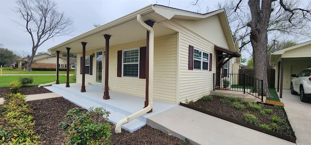 view of side of home with a yard, a porch, and a carport