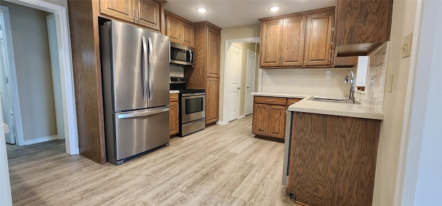 kitchen featuring tasteful backsplash, stainless steel appliances, light hardwood / wood-style flooring, and sink