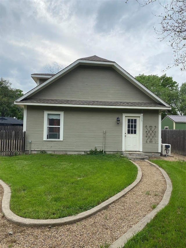 back of property with central AC unit and a lawn