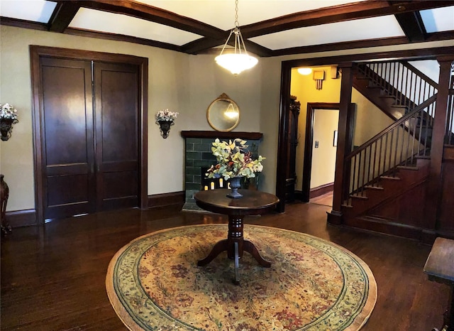 foyer entrance with beamed ceiling, a skylight, a fireplace, and dark wood-type flooring