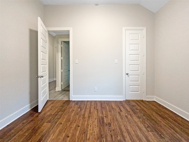 empty room with dark wood-type flooring and vaulted ceiling