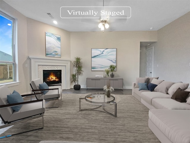 living room featuring ceiling fan, a high end fireplace, and hardwood / wood-style flooring