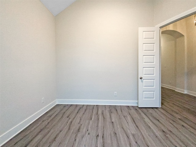 unfurnished room with hardwood / wood-style flooring and vaulted ceiling