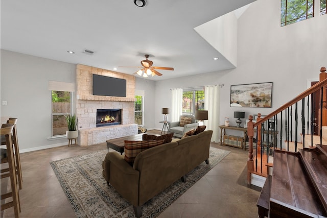 living room with a stone fireplace and ceiling fan