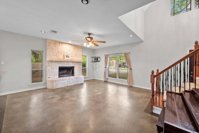 unfurnished living room featuring ceiling fan and a stone fireplace