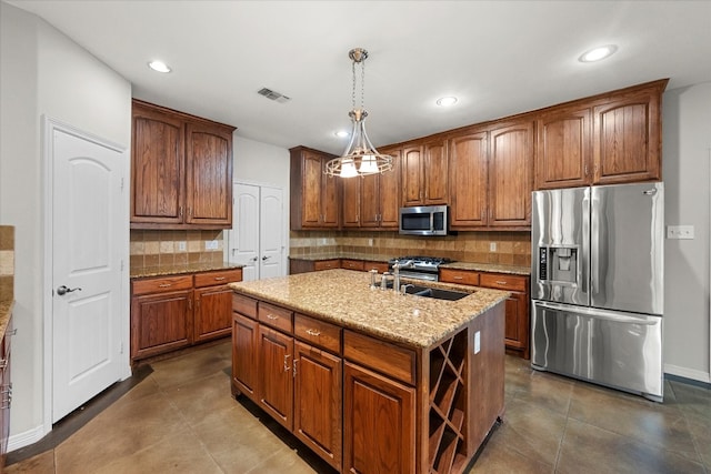 kitchen with an island with sink, hanging light fixtures, sink, backsplash, and stainless steel appliances