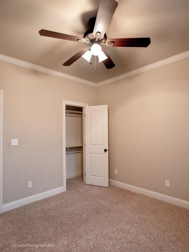 unfurnished bedroom with ceiling fan, a closet, crown molding, and carpet flooring