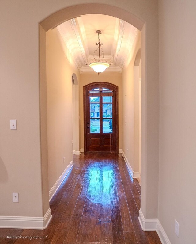 entryway with a raised ceiling, dark wood-type flooring, and crown molding