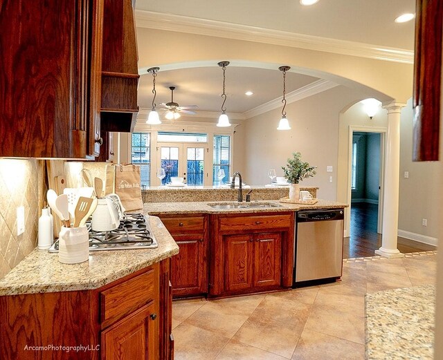 kitchen with hanging light fixtures, stainless steel appliances, light stone counters, ornamental molding, and sink