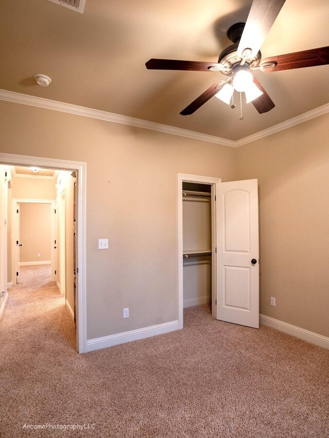 unfurnished bedroom featuring light carpet, crown molding, ceiling fan, and a closet