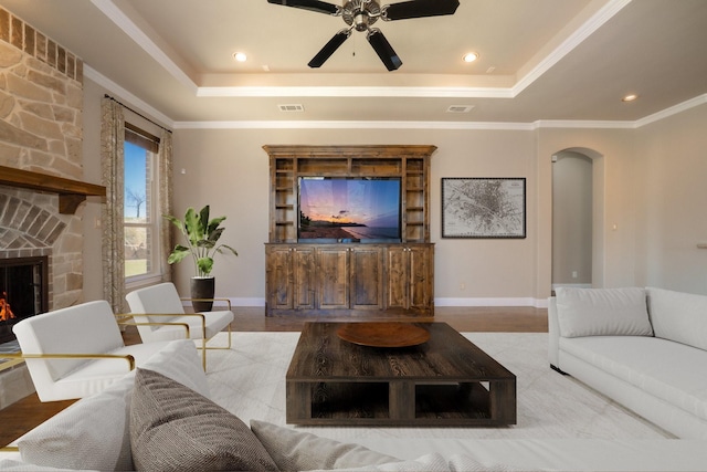 living room with arched walkways, a raised ceiling, visible vents, and ceiling fan