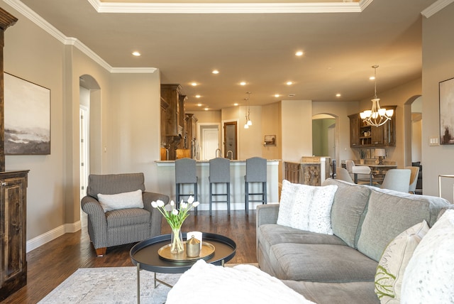 living room featuring a notable chandelier, dark hardwood / wood-style floors, and ornamental molding