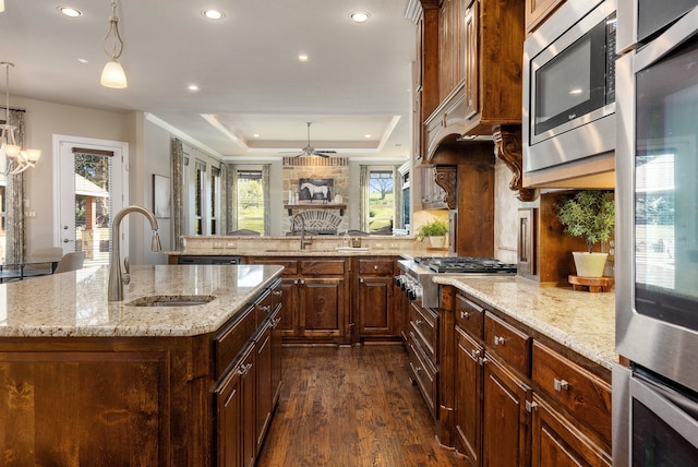 kitchen with sink, decorative light fixtures, a tray ceiling, a large island, and stainless steel appliances