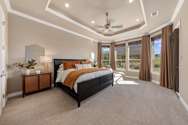 carpeted bedroom with a tray ceiling, ceiling fan, and ornamental molding