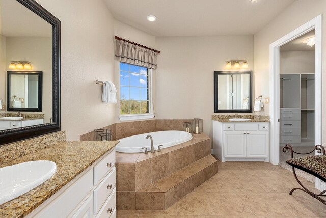 bathroom with tile patterned floors, tiled bath, and vanity