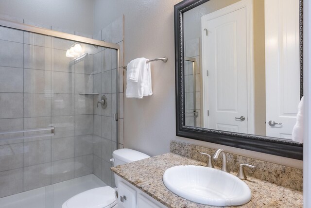 bathroom featuring vanity, toilet, and a shower with door