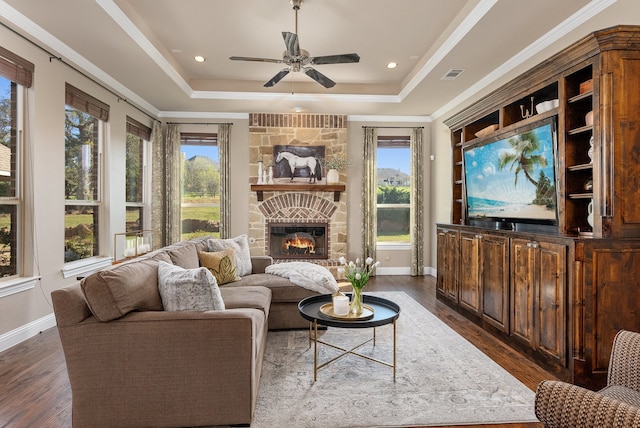 living room with a tray ceiling, dark hardwood / wood-style floors, and a healthy amount of sunlight