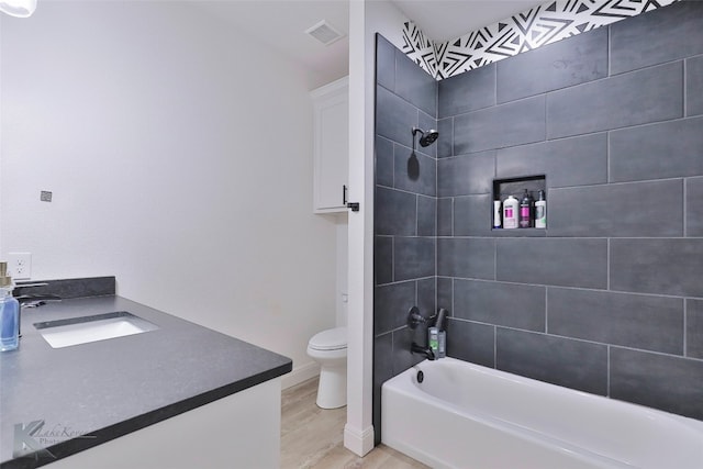 full bathroom featuring toilet, vanity, tiled shower / bath combo, and wood-type flooring