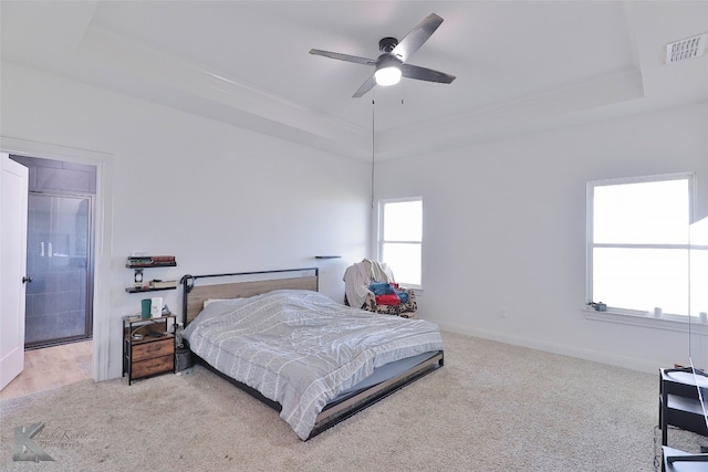 carpeted bedroom with ensuite bathroom, a raised ceiling, and ceiling fan