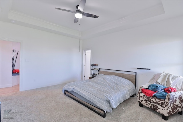 carpeted bedroom with a raised ceiling and ceiling fan