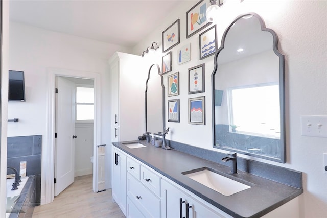 bathroom with double sink vanity, hardwood / wood-style flooring, and a washtub