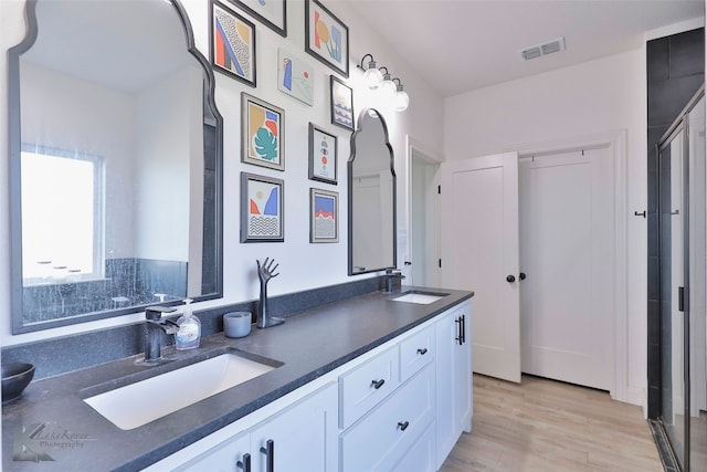 bathroom featuring walk in shower, hardwood / wood-style floors, and dual bowl vanity