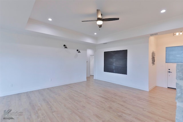 unfurnished room featuring light hardwood / wood-style flooring, a raised ceiling, and ceiling fan with notable chandelier