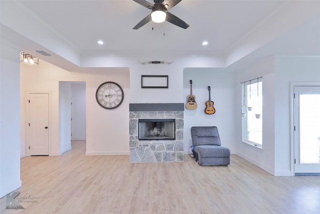 unfurnished living room featuring a stone fireplace, light hardwood / wood-style floors, and ceiling fan