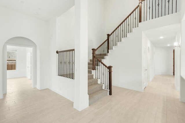 stairs with a towering ceiling and light hardwood / wood-style flooring