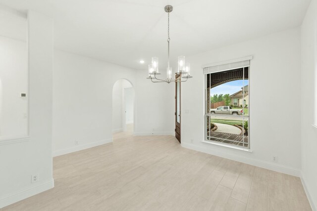 unfurnished room featuring light hardwood / wood-style flooring and an inviting chandelier