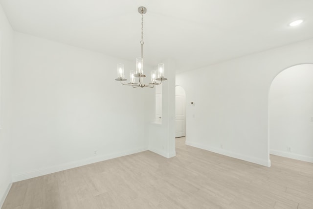 unfurnished room featuring a chandelier and light hardwood / wood-style flooring