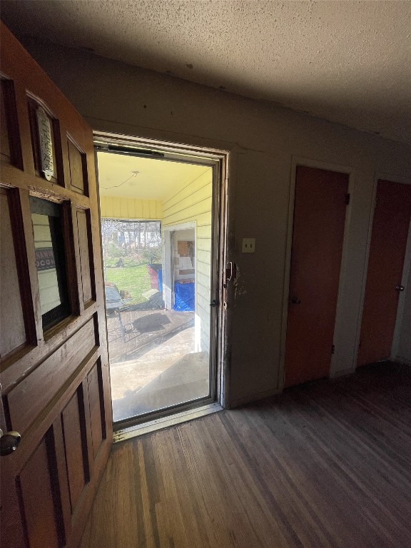 doorway with dark wood-type flooring and a textured ceiling